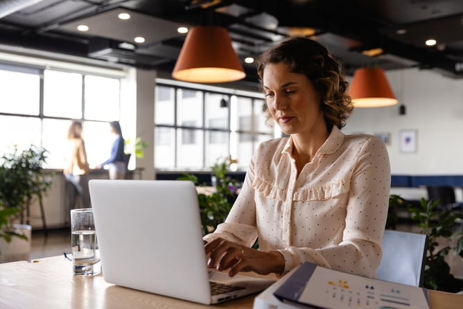 woman using laptop at desk in modern office setting